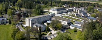 Haus St. Michael Gebäudekomplex des Seniorenzentrums St. Michael in Bad Alexandersbad aus der Luft aufgenommen, eingebettet in grüne Landschaft.